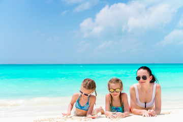 Portrait of young beautiful mother and her adorable little daughters at tropical beach