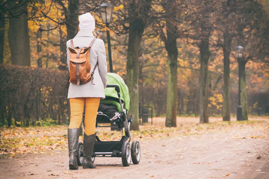 Rear view of mother walking with stroller in park