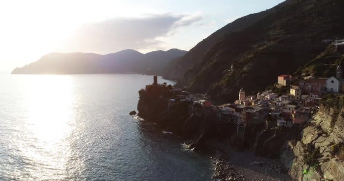 aerial view of travel landmark destination Vernazza, a small mediterranean sea town, Cinque terre National Park, Liguria, Italy. Sunset with cloud and flare. 4k aerial drone forward video shot
