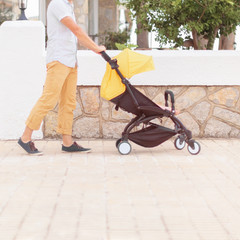 Young father strolling pushchair with a baby