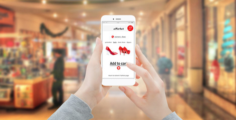 Girl buying red shoes online with modern phone. Blured store in background