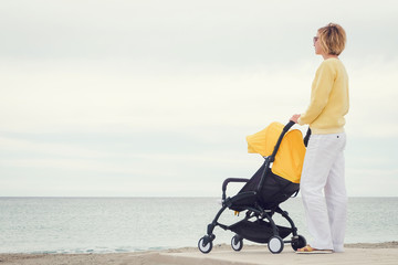 Young mother with stroller looking through the sea