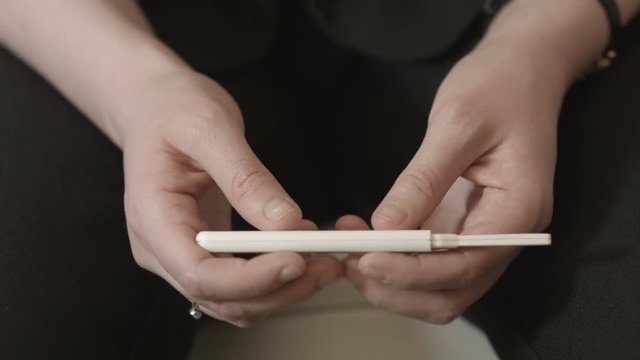 Anonymous female nervously checking a pregnancy test