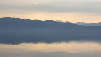 穏やかな湖と朝日に浮かぶ山並み