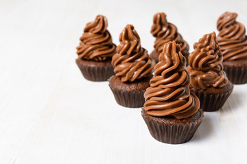 Some chocolate cupcakes on white wooden table
