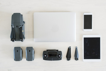 (travel concept) Photographic equipment, Laptop, tablet, smartphone, drone, controller and batteries on a white desk.