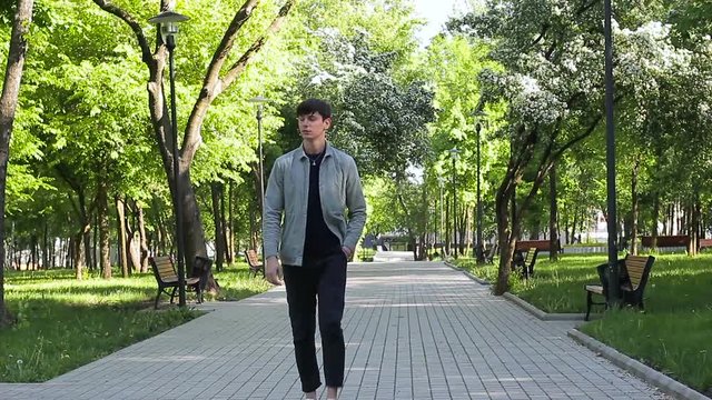 The young guy is walking in the park