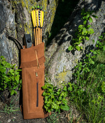 Traditional archery re-curve bow in the quiver with the arrows leaning on a tree