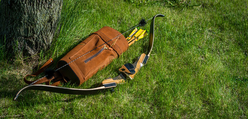 Traditional archery re-curve bow in the grass with quiver of arrows