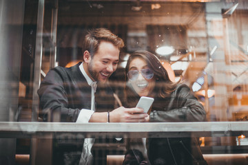 Friends using mobile in a cafe. Couple of lovers having a good time with the cell phone.