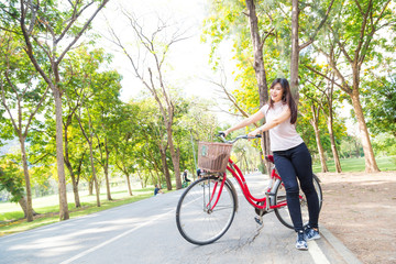 Smiling healthy asian women with bicycle in park