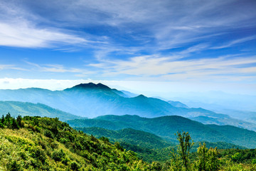Landscape of layered mountain in the mist with dramatic blue sky.
