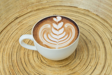cappuccino art hot coffee in cup on wood plate