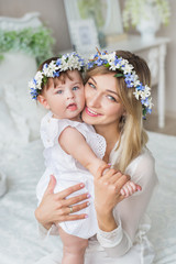 Portrait of smiling young mother with her little baby in a bedroom