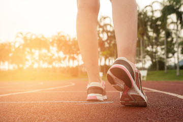 Young woman running during sunny morning on stadium track. health concept.