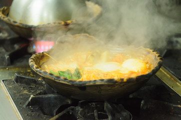 Food steaming in clay pot on gas stove