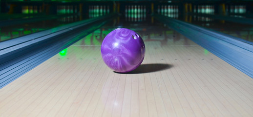 Violet bowling ball on the track. Active leisure. Sport game.