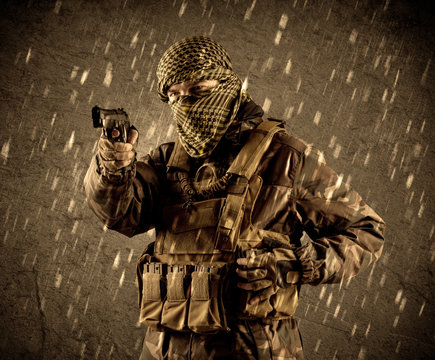 Dangerous heavily armed terrorist soldier with mask on grungy rainy background