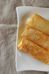 Pancakes stuffed on a white plate on a linen napkin.  Breakfast in eco style 