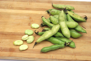 fresh broad beans on bamboo cutting board
