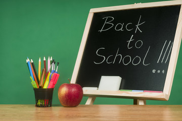 Educational concept - the school equipment and the apple relating to the chalkboard