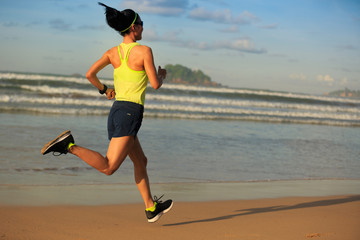 young fitness woman runner running on sunrise beach