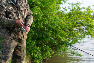 Рыбак ловить спиннингом хищную рыбу на озере.