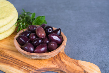 Mediterranean appetizer antipasti tapas calamara olives and garlic pita bread, herbs on wooden plank made from olive tree