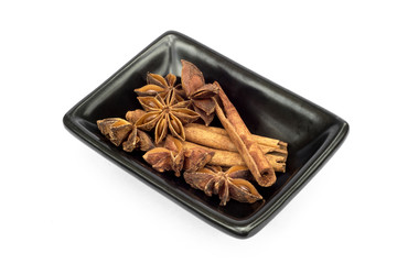 Star anise and cinnamon in a bowl on white background