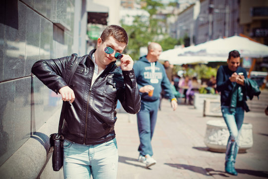 Young man townspeople in black jacket walking around the European city, drinking coffee enjoying life and views of the city