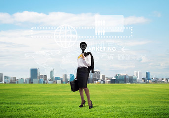 Camera headed woman standing on green grass against modern cityscape