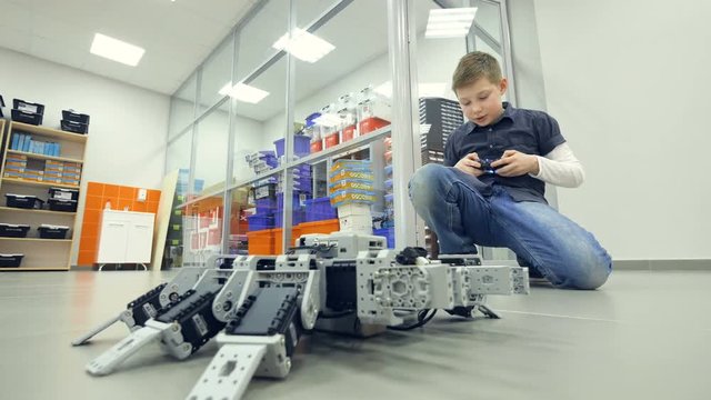The boy controlling the robot scorpion by the joystick. 4K.