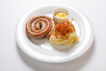 Mashed potato and roasted sausage or bratwurst on white plate