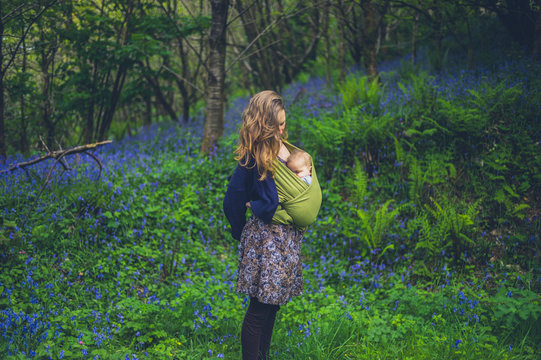 Mother with baby standing in meadow of bluebells