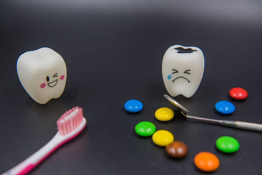 Model Cute toys teeth and colorful candy in dentistry on a black background.