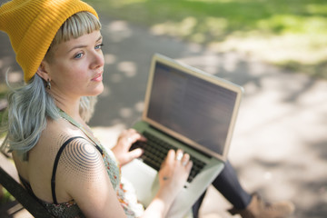 Young woman sat using her laptop in the park