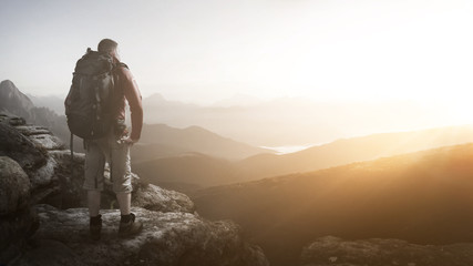 Wanderer steht auf einem Gipfel bei Sonnenaufgang