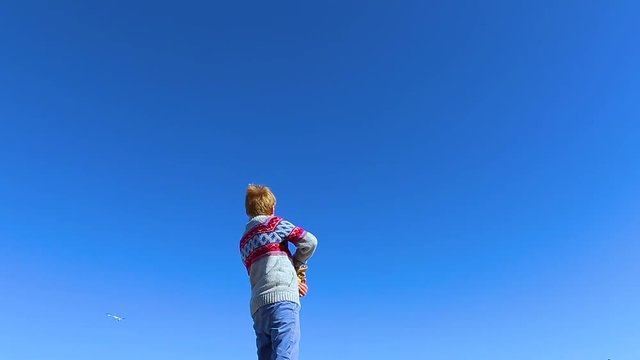 Little 8 year old child feeding beautiful seagulls flying cheerfully in bright blue sky. Birds catching food in air. Real time hd video footage.