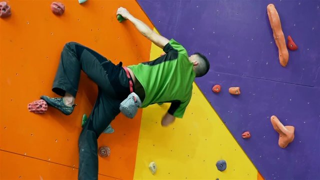 Young Climber Man Climbing Up On Practice Wall In Gym