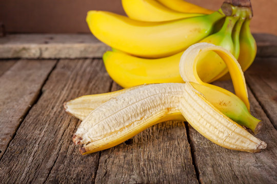 Bundle of bananas and a sliced banana on vintage wooden background, selective focus