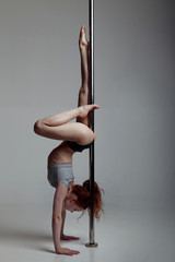 Young woman exercise pole dance gray background