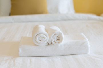 white towel rolled up on white bed sheet in bed room