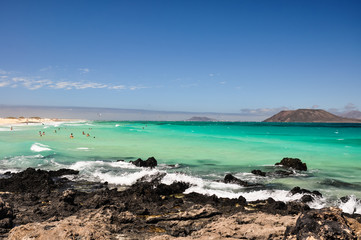 Stunning view of the islands of Lobos and Lanzarote seen from Corralejo Beach (Grandes Playas de Corralejo) on Fuerteventura, Canary Islands, Spain, Europe. Beautiful rocks in the foreground.