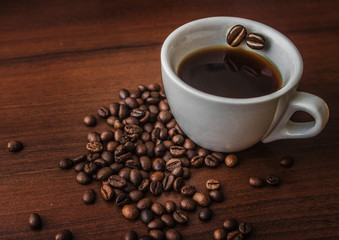 Cup with coffee on a tree with coffee beans