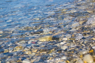 sea pebble beach with multicoloured stones, waves with foam