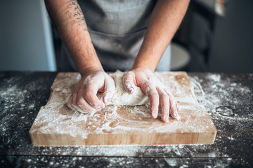 Baker hands kneading the dough with flour