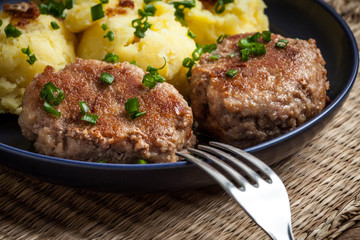 Meatballs served with boiled potatoes on a plate.