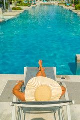 Fototapeta na wymiar Woman with hat at the pool