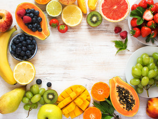 Rainbow color fruits arranged in a circle, strawberries, blueberries, mango, orange, grapefruit, banana, apple, grapes, kiwis on the white background, copy space for text, selective focus