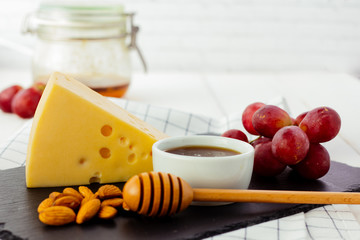 Cheese, almond, grapes and honey on black plate